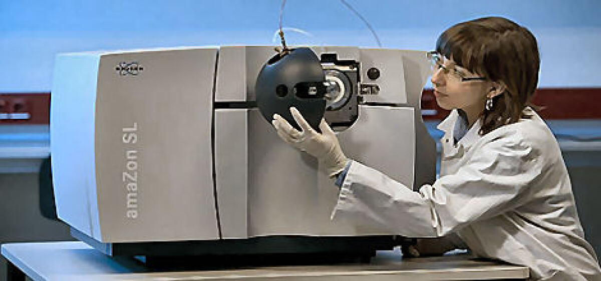 Ein Bild eines Bruker amaZon SL mit einer Frau, die in Laborkleidung den Einlass am Gerät kontrolliert.