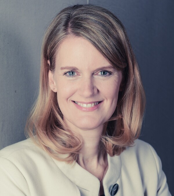 Porträtbild von Prof. Dr. Isabell van Ackeren. Bild in warmen Farbtönen gehalten. Hellgrauer Hintergrund, Kleidung cremefarbene Jacke .