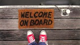 Turschuhe vor Fußmatte mit der Aufschrift Welcome on board
