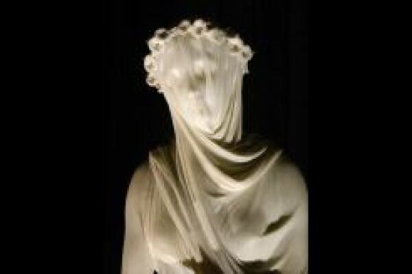 Eine antike Statue, welche eine Frau darstellt wird von einem transparenten Tuch verhüllt, sodass sie nur schemenhaft zu erkennen ist. 