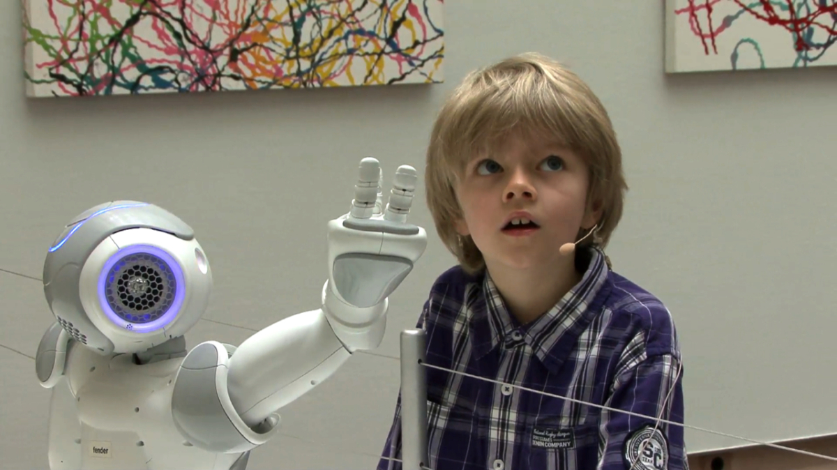 Ein Kind folgt mit dem Blick der Zeigegeste eines Roboters.