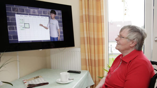 Eine ältere Person sitzt vor einem Bildschirm, auf dem ein Terminkalender und ein virtueller Avatar abgebildet sind.
