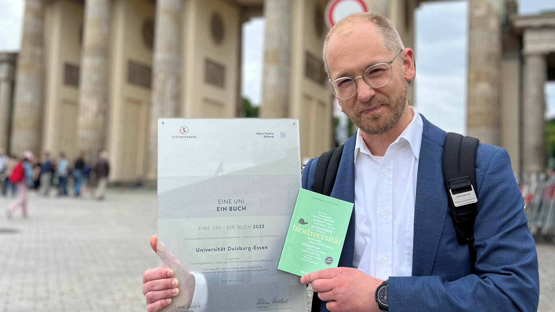 Portrait von Florian Lese mit dem Preis vor dem Brandenburger Tor 
