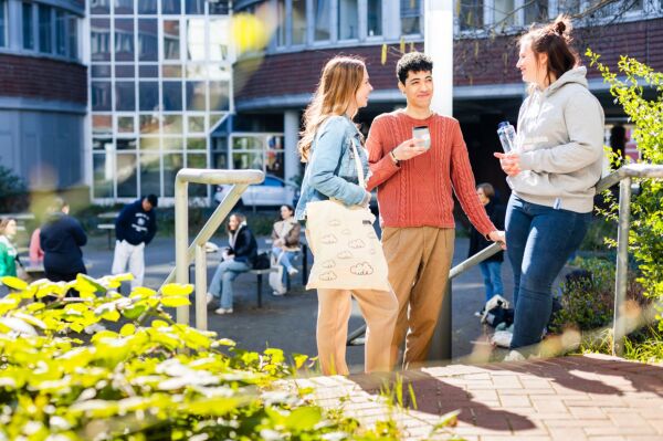 Studierende genißen ihre Freizeit. Lachen und unterhalten sich auf dem Campus.