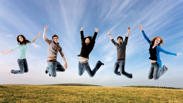 Junge Menschen springen auf einem Hügel fröhlich in die Luft