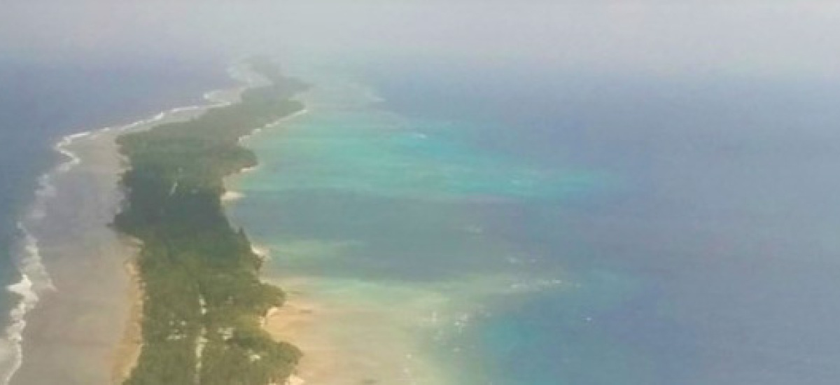 The picture shows the Marshall Islands from above - a long, small strip of land in a blue sea.