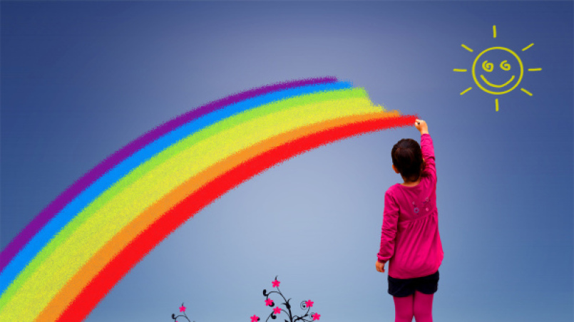 Kind da einen sehr großen Regenbogen an den Himmel malt, darüber eine gezeichnete lachende Sonne