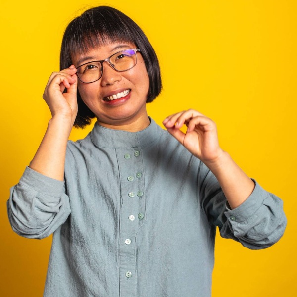 Photo of an Asian woman with glasses, smiling at the camera