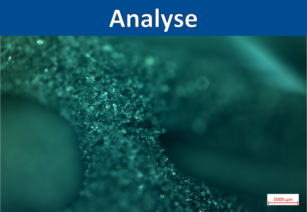 'Analyse' in weißer Schrift auf blauem Balken; darunter grüne, raue, kristalline Mikrostruktur eines Bauteils (Maßstab 2000 µm).