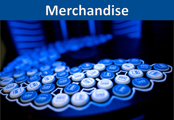'Merchandise' in weißer Schrift auf blauem Balken; auf einer runden Bauplattform liegen 3D-gedruckte Einkaufswagenchips in Weiß und Blau mit UDE-Logo.