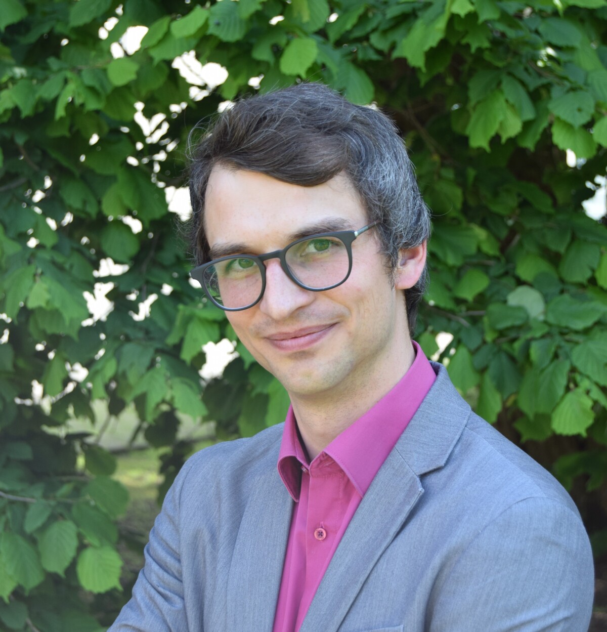 Bild einer Person vor grünen Blättern