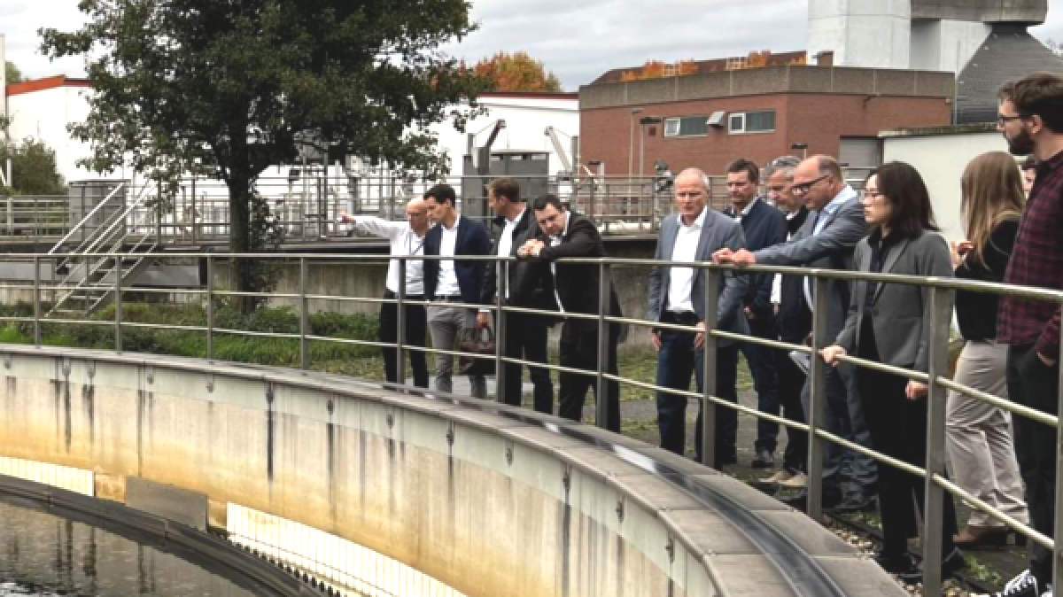 Project participants are standing behind a railing at the sewage treatment plant in Duisburg-Vierlinden and examining a clarifier.