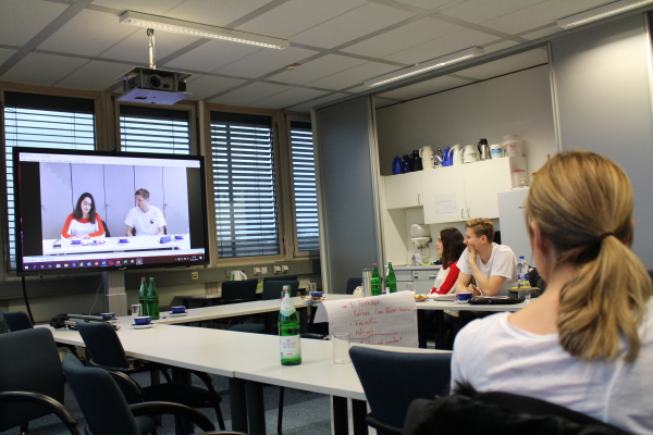 Das Foto zeigt Studierende, die sich die Videoaufzeichnung ihres simulierten Meetings anschauen