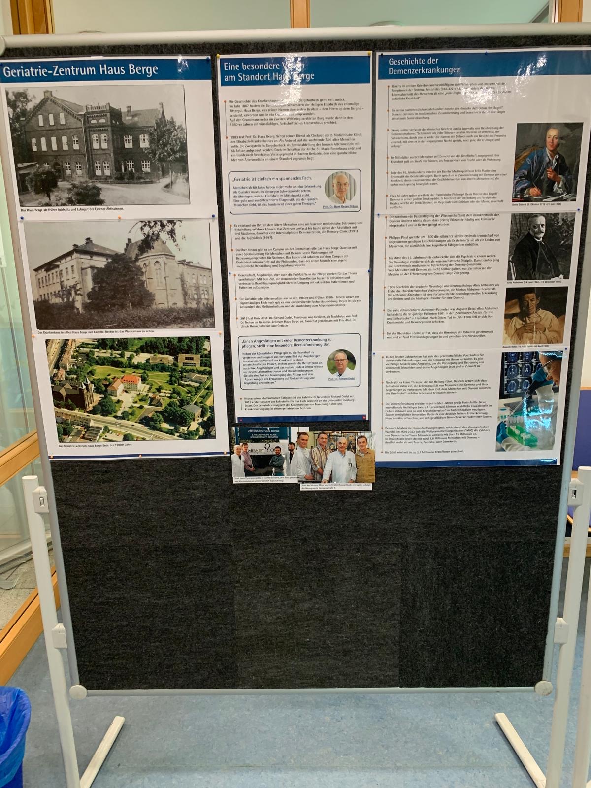 Ein Bild einer Pinnwand aus der Ausstellung während des Tages der offenen Tür. Auf der linken Seite der Pinnwand ist das Geriatrie-Zentrum Haus Berge früher zu erkennen. In der Mitte und auf der rechten Seite sind Texte zu zu sehen.