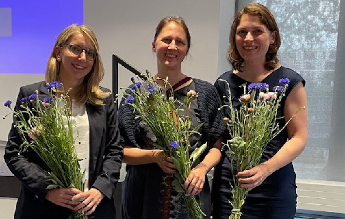 "Melitta Gillmann, Judith Purkarthofer und Eva Gredel vor der Bühne des Glaspavillons, mit Blumensträußen in den Händen