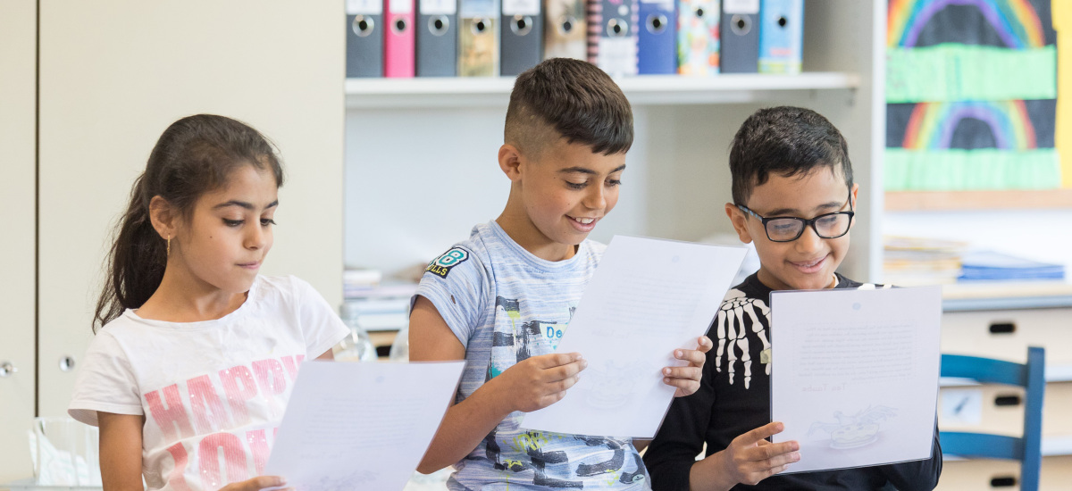 Drei Kinder lesen gemeinsam einen Text vor