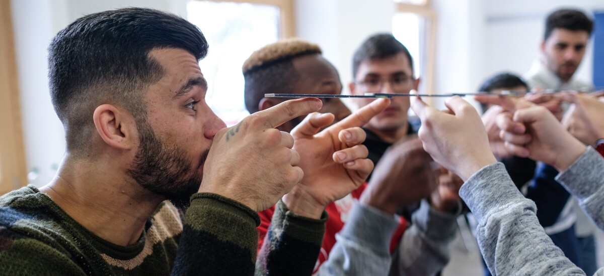 Mehrere Personen balancieren gemeinsam einen ausgeklappten Zollstock