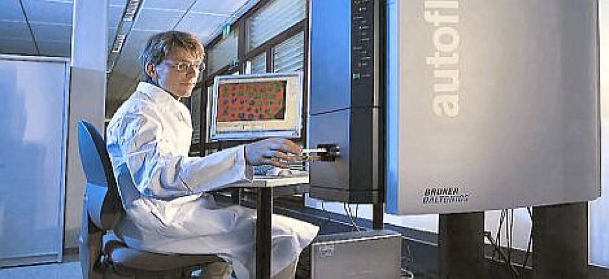 Ein Bild eines Bruker autoFlex Speed mit einer Frau in Laborkleidung, die daran arbeitet.