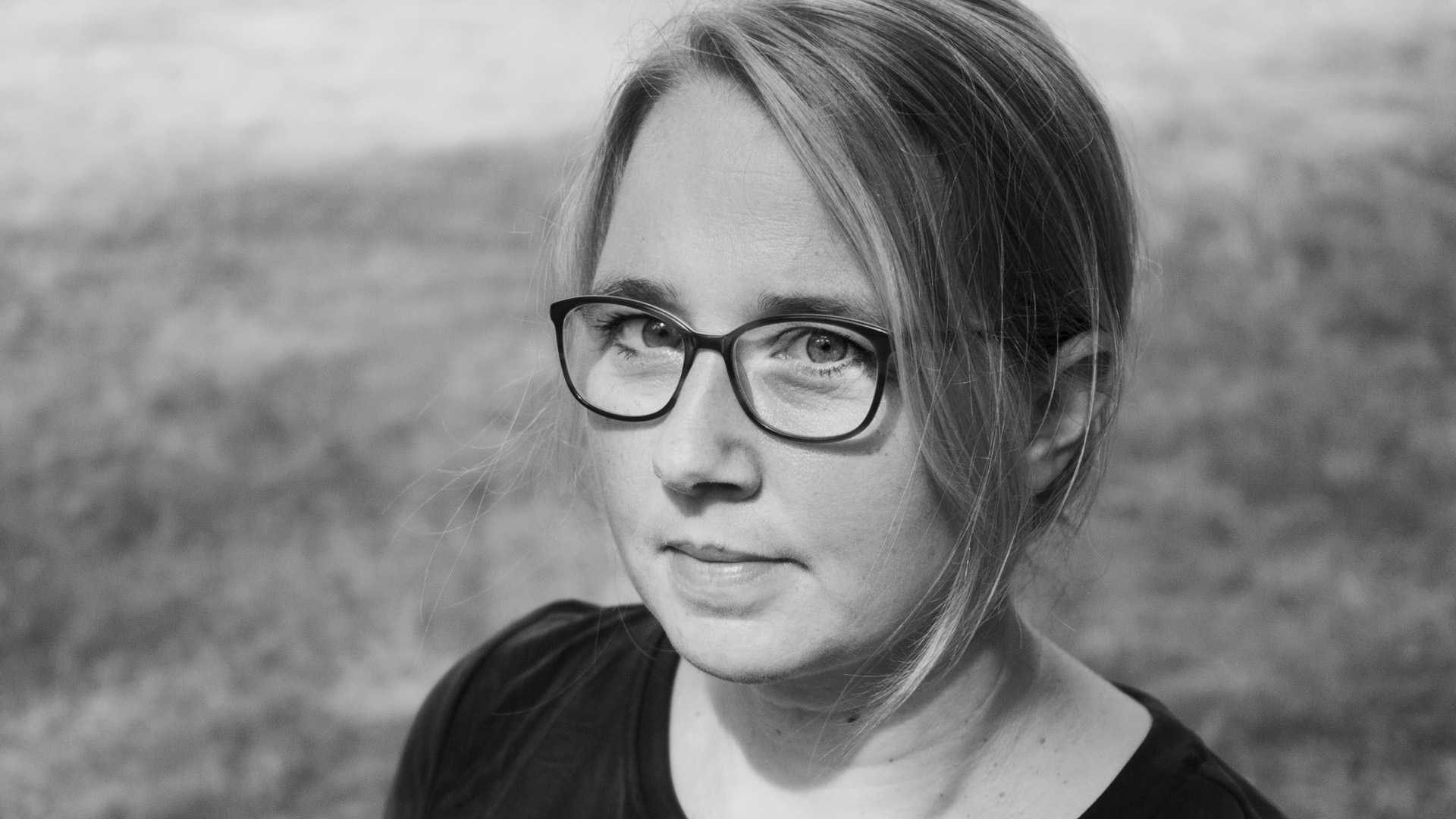 Portraitbild von Karolin Viseneber. Sie hat ihre blonden Haare zusammengebunden und trägt eine Brille