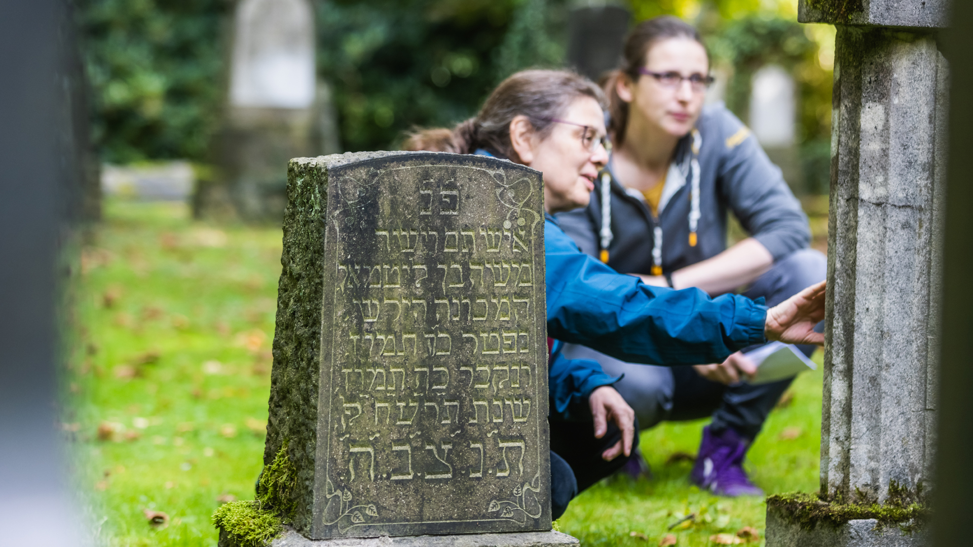 Zwei Mitarbeiterinnen des Steinheim-Instituts untersuchen eine Grabinschrift auf dem jüdischen Friedhof in Essen-Segeroth. 