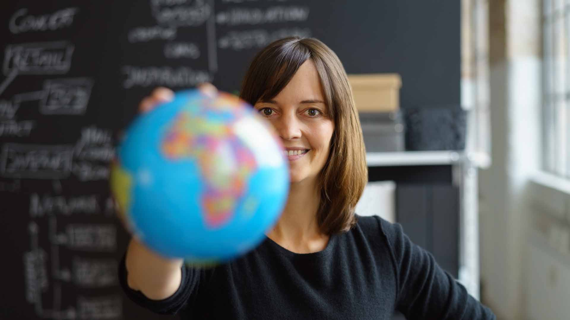 Symbolbild: freundlich lächelnde Frau hält einen Globus 