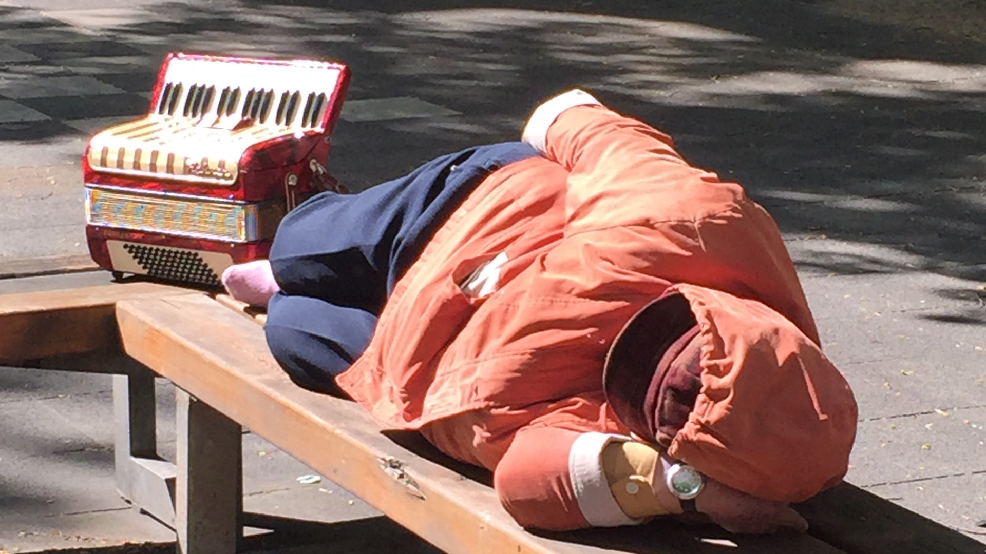 Ein Straßenmusikant schläft auf einer Bank