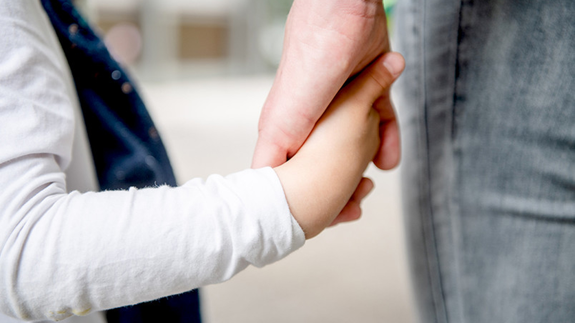 Kind mit einem Elternteil Hand in Hand
