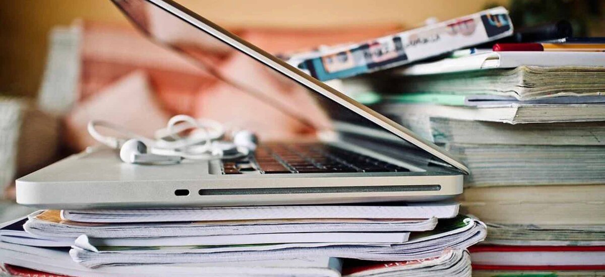 Bücher- und Heftestapel mit Notebook und Kopfhörer