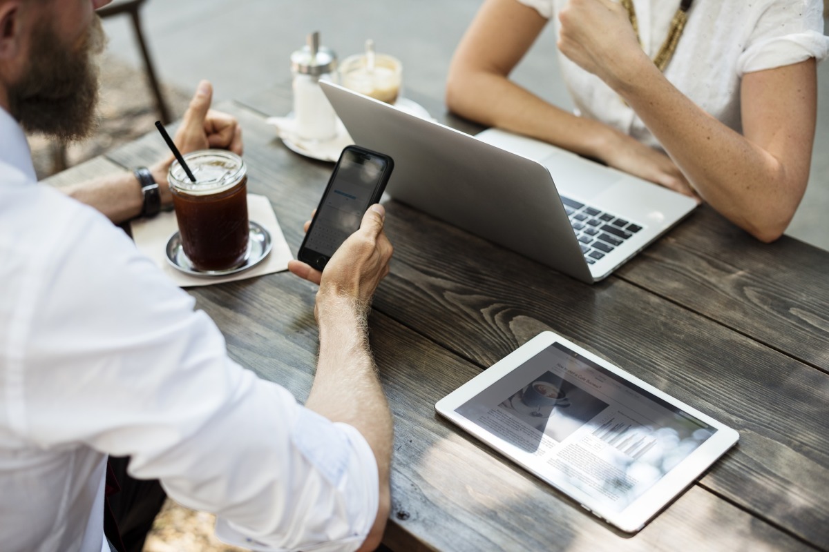 (Symbolbild) Auf dem Bild sind ein Mann und eine Frau an einem Tisch zu erkennen, die sich gegenübersitzen. Ihre Gesichter sind nicht zu sehen. Sie haben auf dem Tisch zwischen sich zum Arbeiten einen Laptop und ein Tablet.