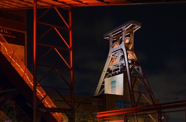 Zu sehen ist der von hinten rot beleuchtete Turm der Zeche Zollverein in Essen bei Nacht.